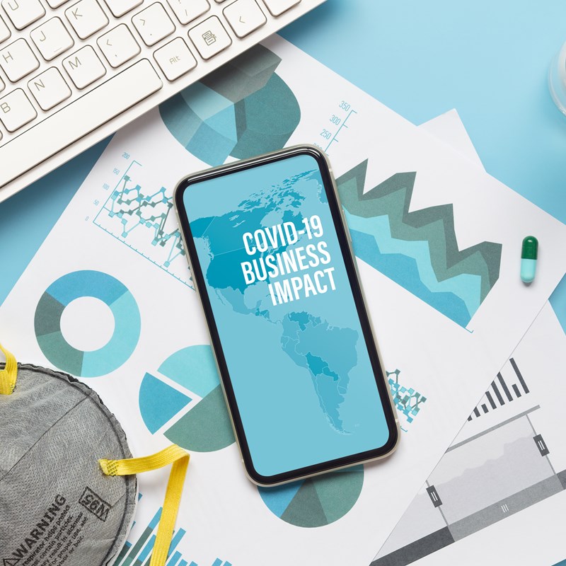 Mobile phone and keyboard with 'Business Covid  impact'