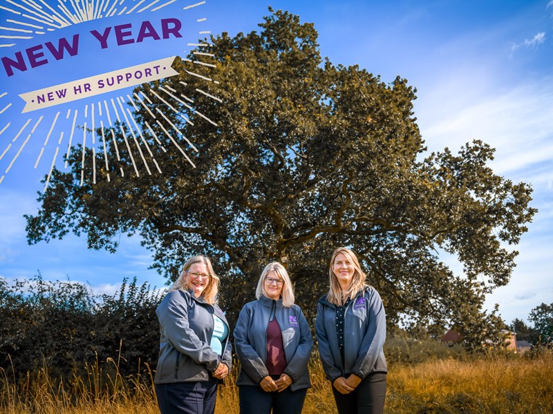 Three people stood outside by a tree