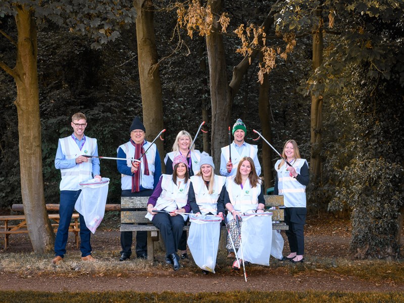 8 people holding litter pickers in the forest