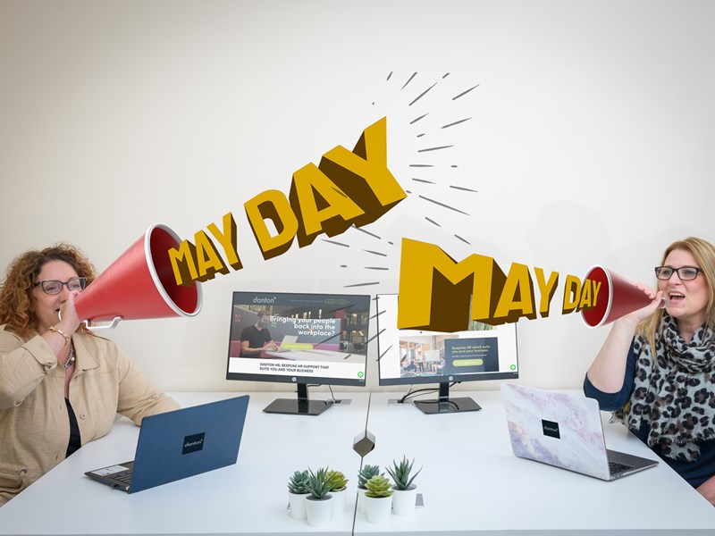 Two people sat at office desks using loud speakers to say "May Day"